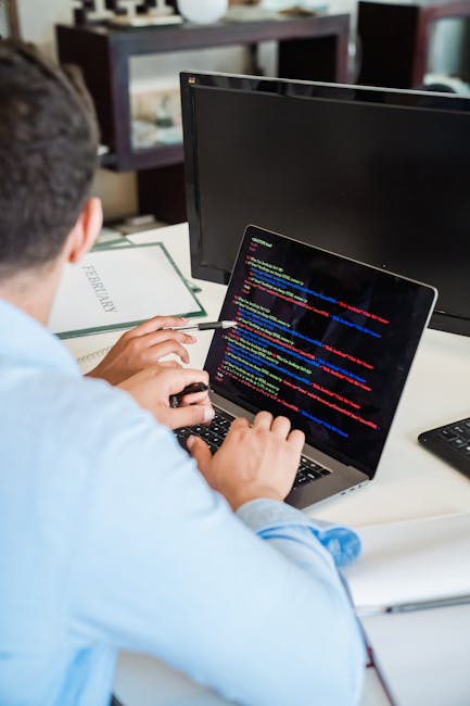 A close-up photograph of a computer screen displaying lines of programming code in various colours, including red, blue, green, yellow, and white. The code consists of functions, variables, and syntax